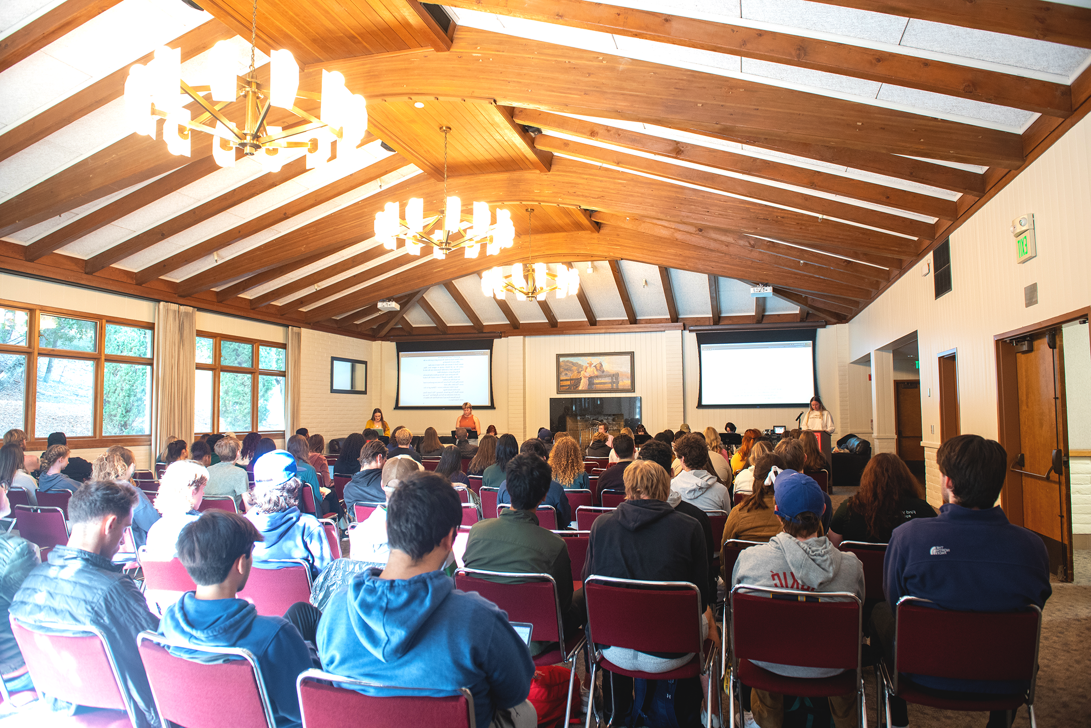 A large crowd of students in Claeys Lounge watching a staged reading of Angels In America